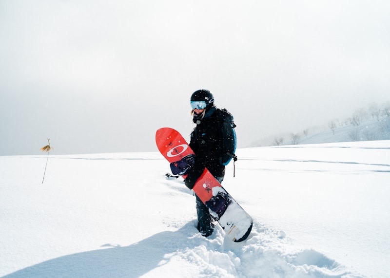 Snowboarder loopt met zijn board door de verse sneeuw